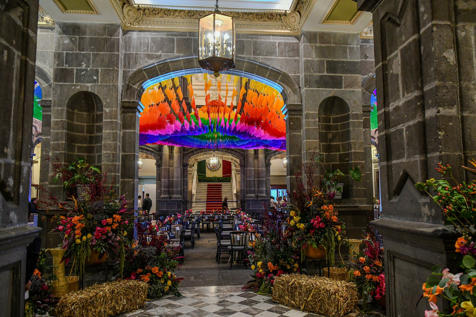 Montaje en palacio con papel picado, flores y mesas de gala